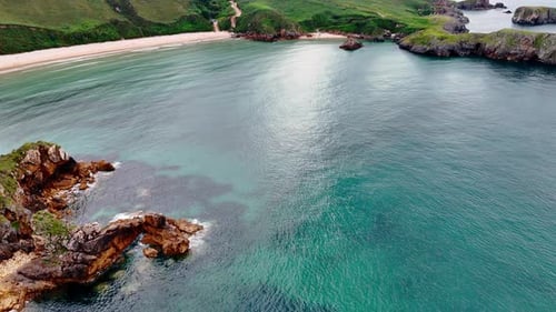 Stunning azure waterscape at the rocky coast with beautiful sandy beach.