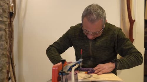Low angle view close-up of a concentrated carpenter cutting a piece of wood in workshop