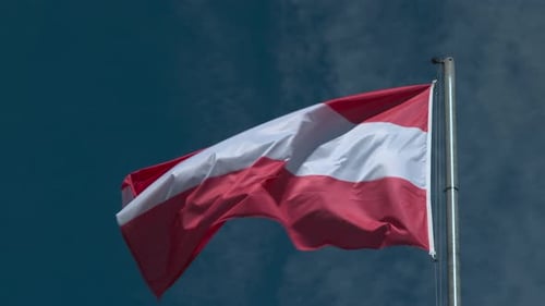 Red and White Flag Waving Against Blue Sky