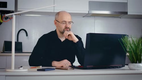 Bearded Adult Man Using Laptop Studying Online Working From Home on Internet Focused Thoughtful Man