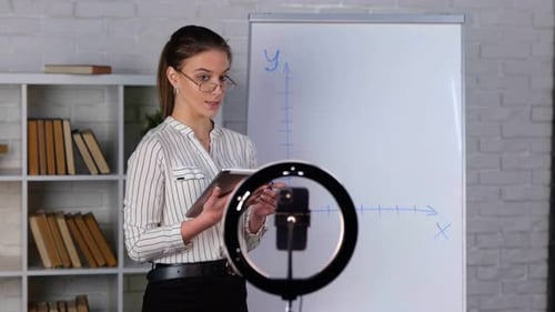 Young Woman Explaining Graph on Whiteboard for Camera