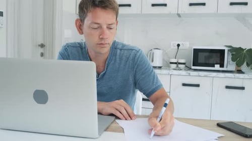 Man Working at Desk with Laptop and Paper