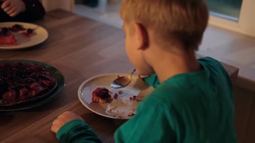 Child eating delicious birthday cake at wooden table