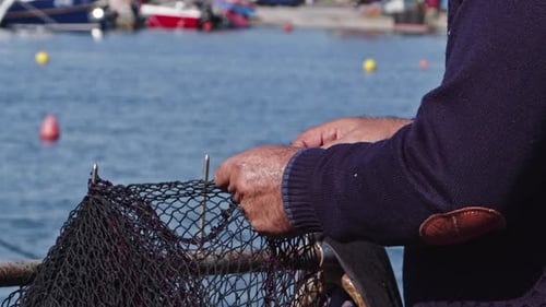 Fisherman Repairing Mending Torn Fishing Nets In The Marina
