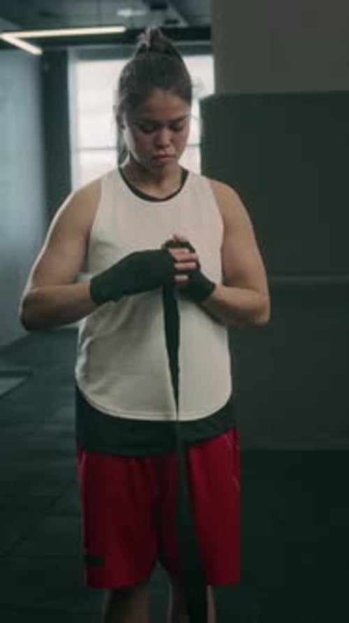 Woman Wrapping Bandage Around Wrist in Gym