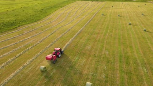 Tractor Baling Hay in Green Field Aerial View