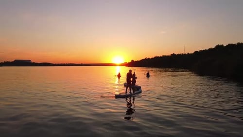 Paddleboarding Silhouettes on the Lake at Sunset