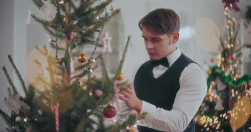 Young Adult Man Decorates Christmas Tree at Home