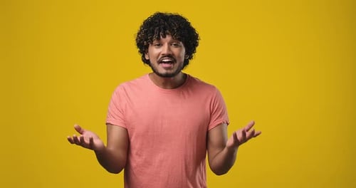 Amazed Indian Man Shocked Saying WOW Surprised to Camera Standing Over Orange Studio Background