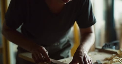 Female woodworker skillfully carves wood in bright workshop during the day