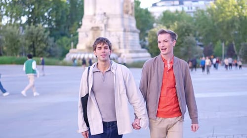 Happy Gay Couple Holding Hands Walking in the Park
