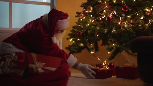 Santa Claus Putting Gifts Under Christmas Tree