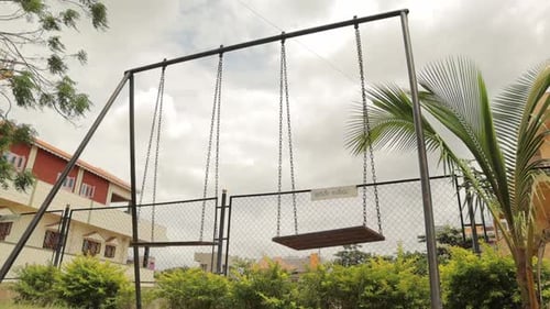 Empty Children swing at park swinging heavily with wind.
