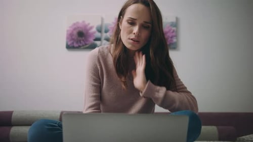 Woman using laptop while sitting on sofa indoors