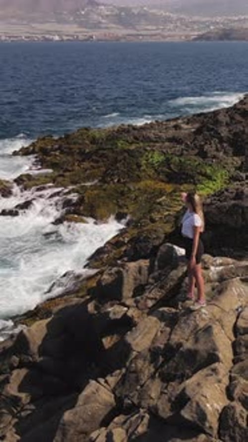 Woman enjoying the ocean view from a rocky cliff