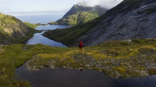 Attractive Woman in Trekking Clothes with Stands on Top of a Mountain Range and Looks Around High in