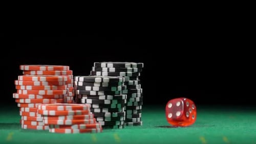 Casino Chips and a Red Die on Table