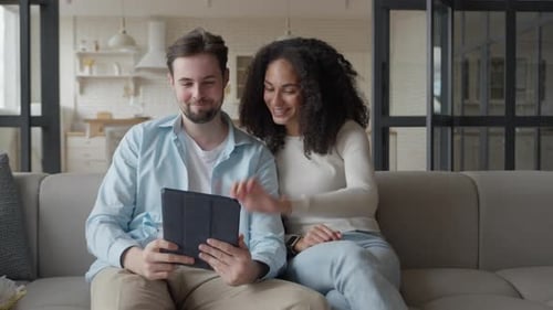 Cheerful Couple Enjoying Tablet at Home on Sofa