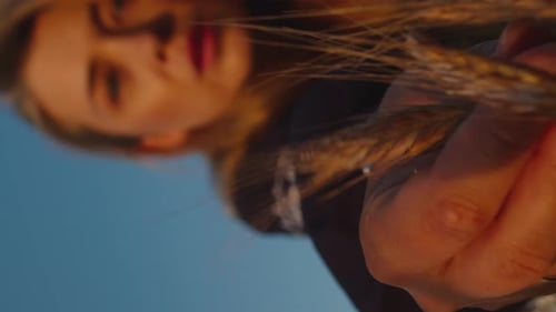 Woman Holding Golden Wheat Stalks at Sunset