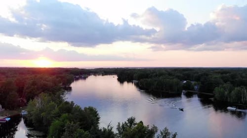 Rising drone shot of sunset over a small lake in Michigan during summertime