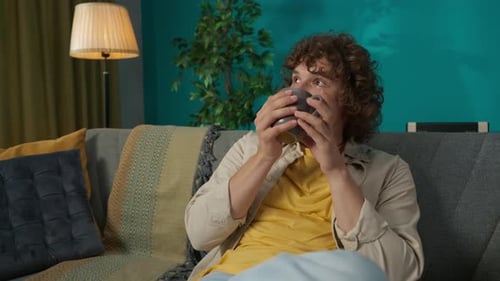 Man Drinking From Mug While Relaxing on Couch