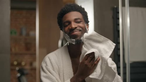 Man Wipes Face After Shaving in Bathroom