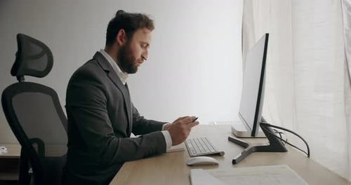 Junger Mann, Freelancer in grauem Anzug, der Laptop benutzt, studiert und zu Hause online arbeitet