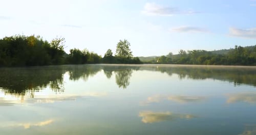 A view of the lake surface at sunrise when the mist rises above the water and the sun shines behind