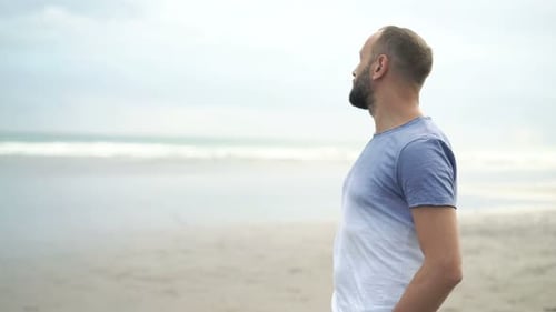Young man enjoys seaside view on tropical beach during summer vacations