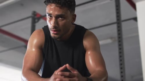 Sweating and resting, man in gym taking break from workout