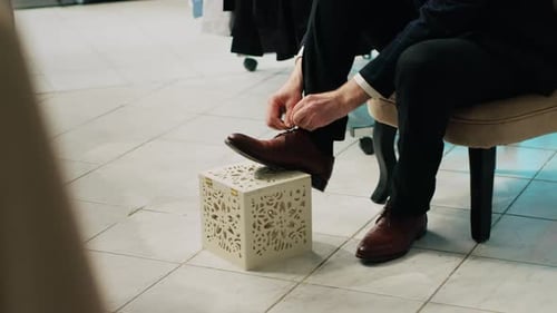 Man Tying Shoe Laces in Clothing Store