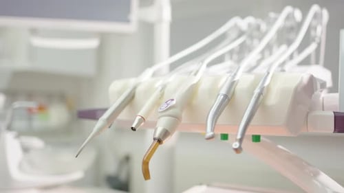 Close-up view of hygienic metal dental tool set as one is picked up by hand
