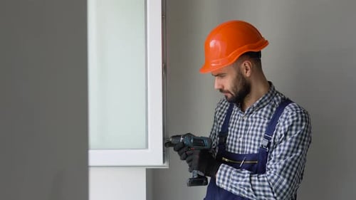 A Repairman in Uniform and Helmet Fixing Pvc Windows in New Apartment