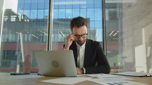 Homme d'affaires concentré et commerçant fatigué L'homme enlève ses lunettes et se frotte les yeux fatigués s'assoit