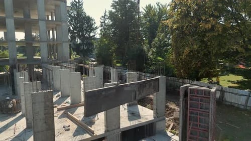Arbeiter führt Betonbalkeninstallation auf der Baustelle Ein Bauarbeiter in Sicherheitsausrüstung