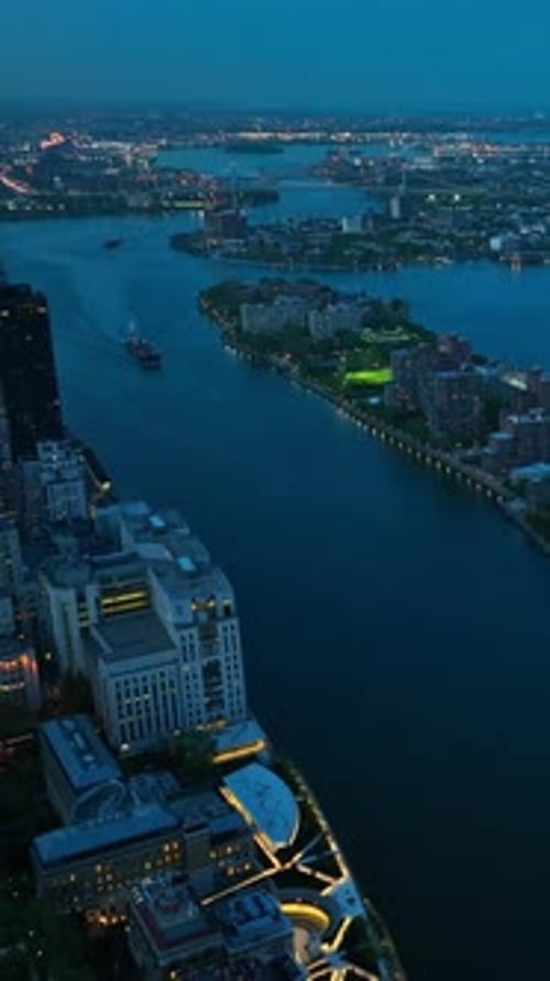 Evening slowly falling on New York city. Top view on the river and buildings with luminous lights