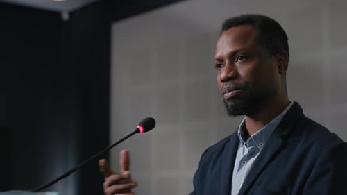 Speech Of Political Speaker At Meeting Room Of Modern Business Center. Adult Black Man In Suit Ex...