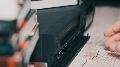 Hand Inserts VHS Tape into Vintage VCR Player