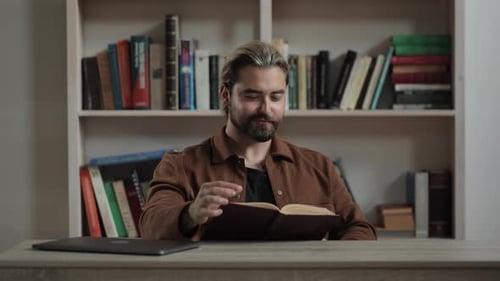 Man Reading a Book at Table Indoors