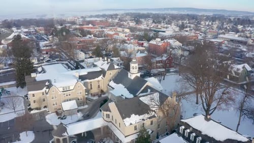 Winter snow, snowflakes on small town and church in USA. Aerial establishing shot. Cinematic gorgeou