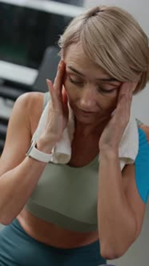 Tired Sportswoman Drinking Water after Workout in Gym, Vertical