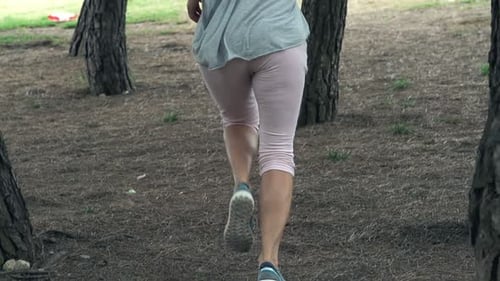 Young sporty woman jogging in park training for marathon in super slow motion