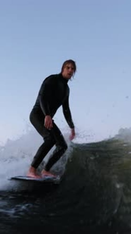A Skilled Surfer Showcases Balance and Agility While Riding a Wave at Dusk Capturing the Essence of