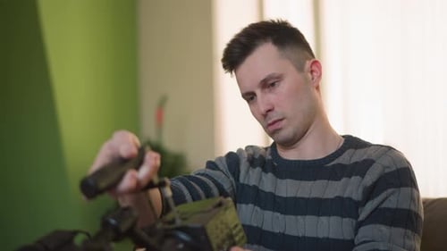 Man Adjusting Camera with Microphone in Hands Focused on Equipment Setup in Home Studio