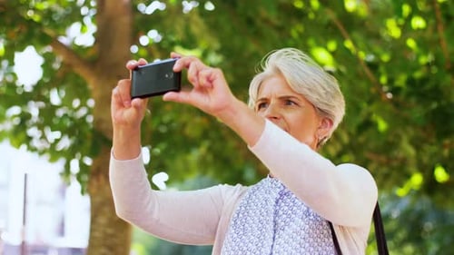 Elegant Senior Woman Using Smartphone in Sunny Park