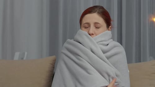 Une femme est assise sur le canapé et se sent malade et utilise des mouchoirs pour se soulager à la maison