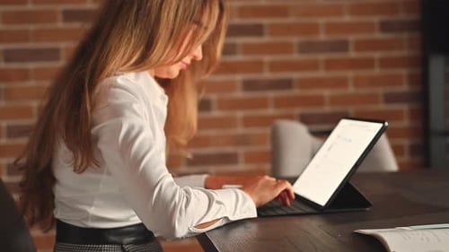 Designer woman working on tablet pc, reviewing project blueprints at the office