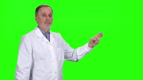 Mature Doctor Pointing to Green Screen Presentation Space
