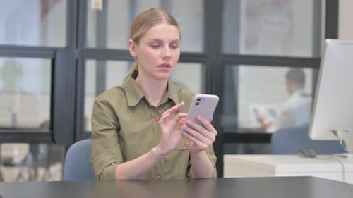 Young Businesswoman Shocked by Loss on Phone in Office
