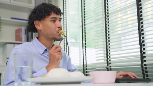 Asian young businessman eating Chinese dimsum while working in office.